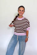 A woman modeling a short-sleeve knit sweater with brown and off-white horizontal stripes and light pink ribbed trim, paired with light blue jeans, against a plain white background.